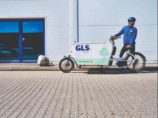GLS driver with bicycle delivering parcels